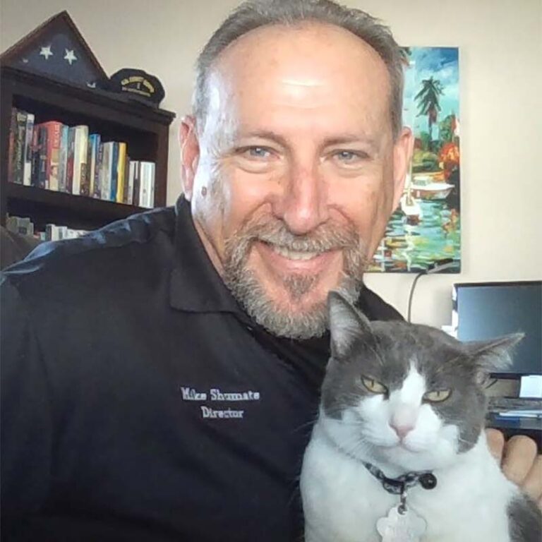 Michael Shumate with a grey and white cat smiling at the camera