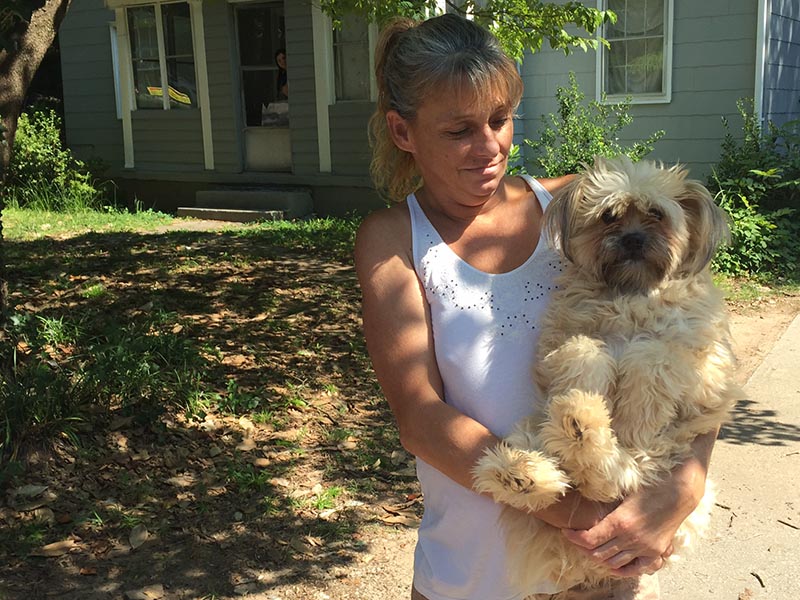 woman holding dog outside house - New Study: Pet Rental Fees Hurt People and Their Pets